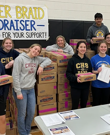 Student team celebrating their Butter Braid fundraiser with stacked cases